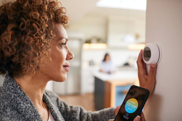 Woman adjusting a smart thermostat with an app on her phone