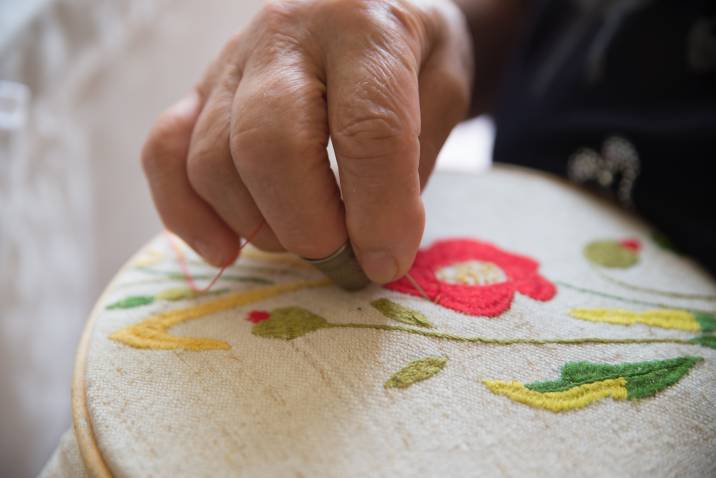 closeup hands, senior woman doing embroidery to earn money