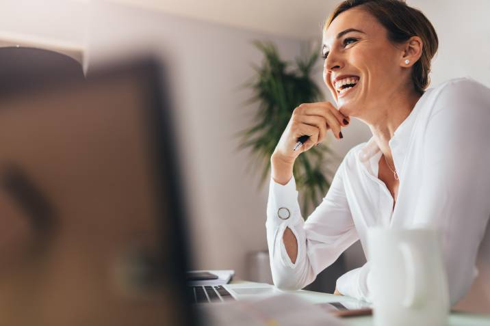 happy female worker sitting on her office desk