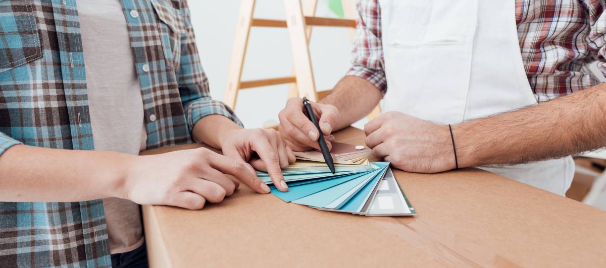 Closeup hands. Couple choosing colour swatches for painting a house