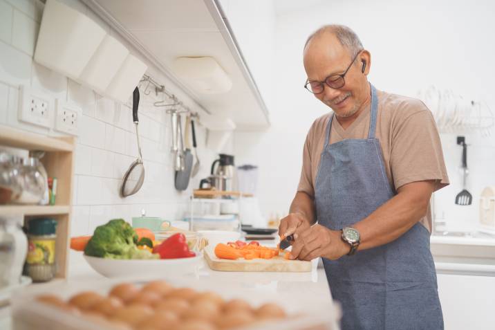 elderly Asian man cooking food to sell