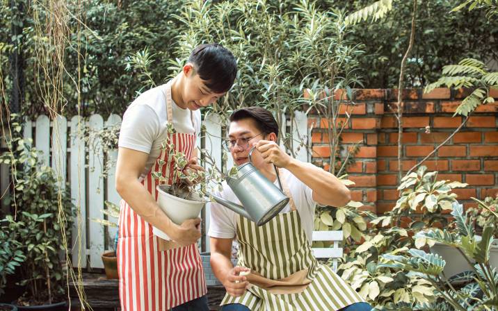 Handsome Asian couple watering plants in outdoor garden to earn extra money gardening