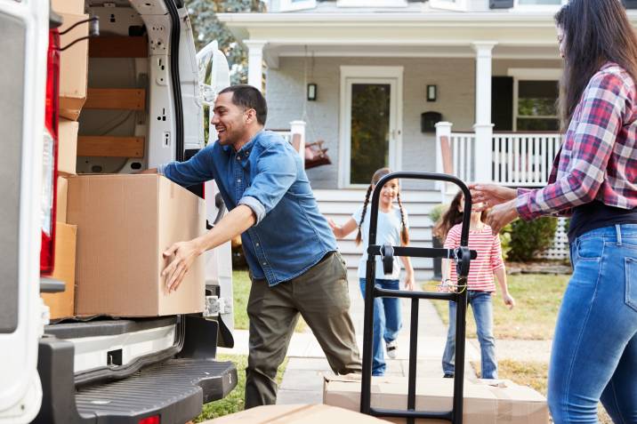 man helping mother and children unload boxes from moving van