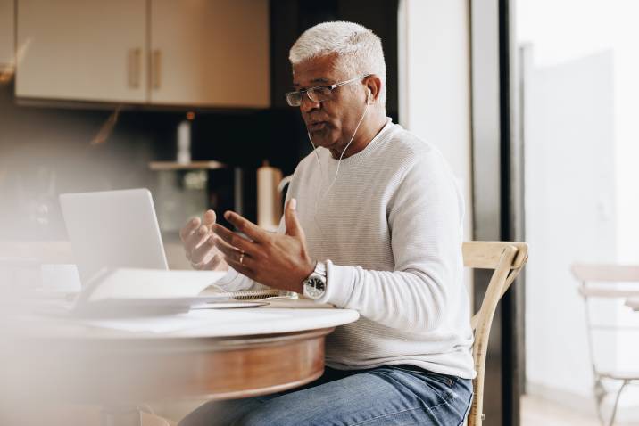 retired businessman coaching someone virtually in his home office