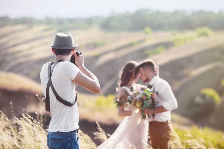photographer taking pictures of bride and groom outdoors, summer part-time job