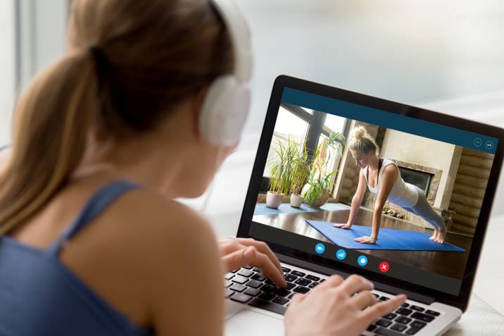 Personal trainer online side hustle. Back view of millennial female yoga teacher guiding her student through a plank 