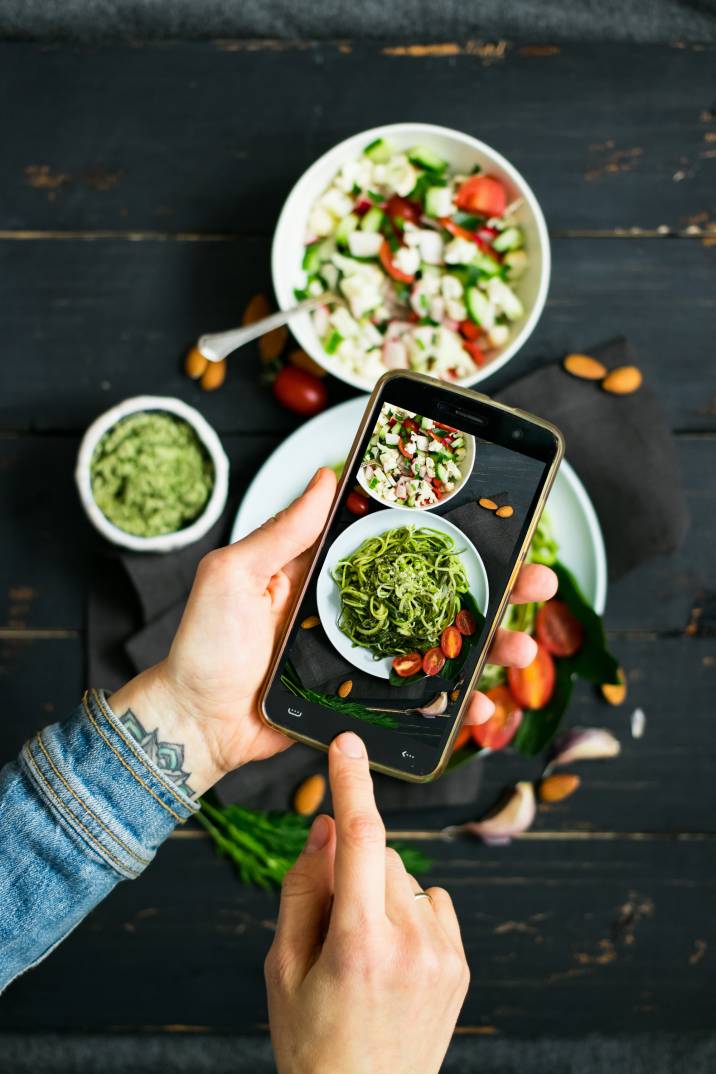 Closeup woman hands takes photo of zucchini pasta to sell stock photos online