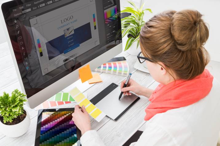 Graphic designer working on computer, holding color swatch samples