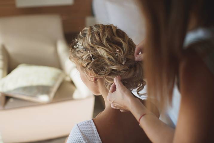 Stylist fixes hair of the bride, hair and makeup side hustle