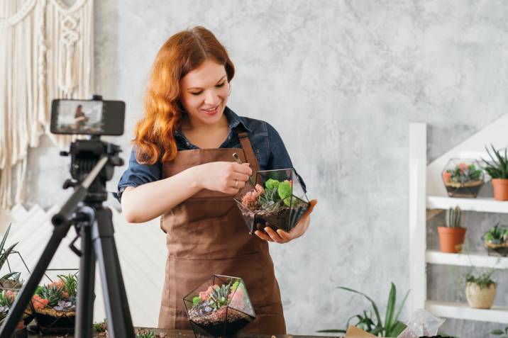 Woman using smartphone to record home gardening online course, planting succulents