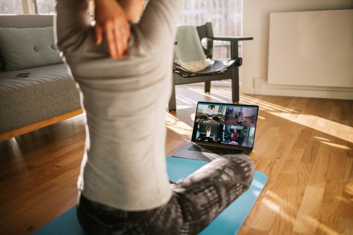 Fitness coach teaching yoga online to group of students