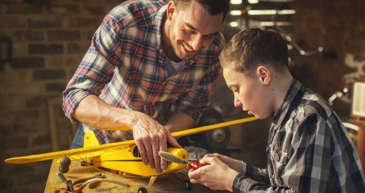 Toy assembly specialist helping boy assemble a toy airplane