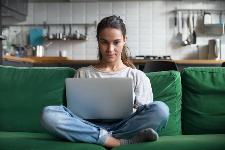 Working mom writing an article to earn extra income, sitting on sofa