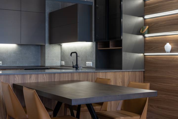 Modern kitchen with black wall, table, and chairs