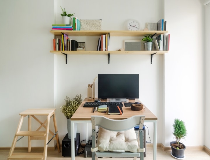 Small office desk with wooden shelves and decor
