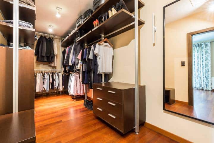Private spacious walk-in closet full of clothes and shoes with wooden wardrobes