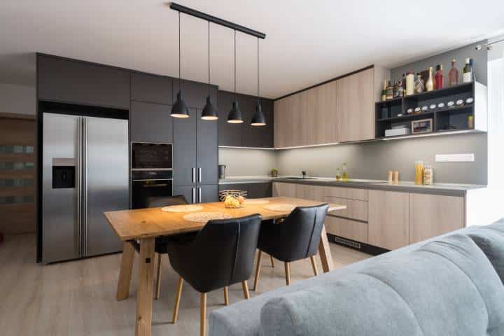 Dining table in kitchen of modern house with even pendant lighting