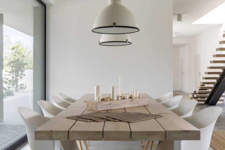 Room with wood dining table, white chairs and industrial lamp