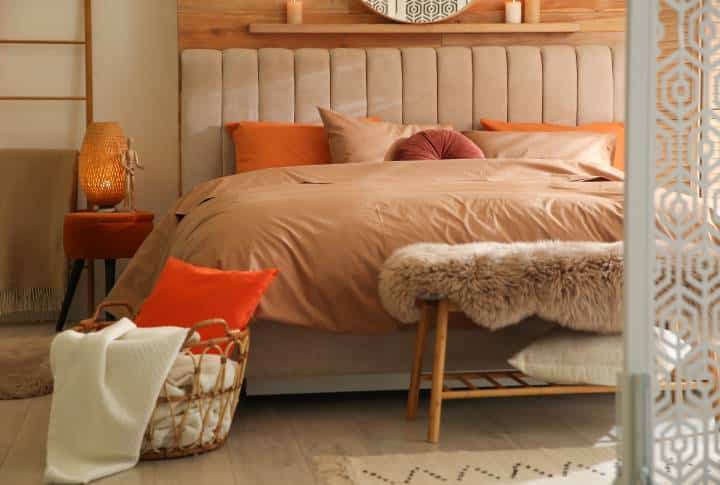 Bed with orange and brown linens in cozy bedroom