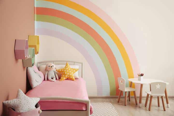 Cute child's room interior with beautiful rainbow painted on wall