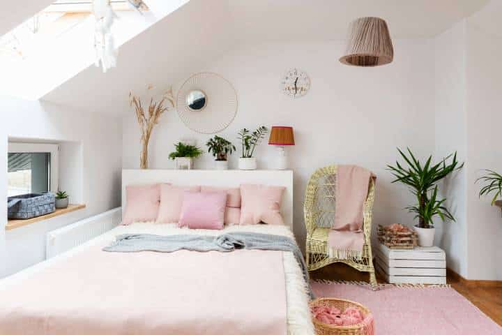 White interior of bedroom in the attic with double bed with pink stylish pillows