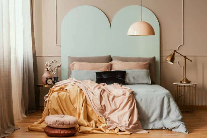 Pastel blue, pink and orange bedding on double bed in chic bedroom interior