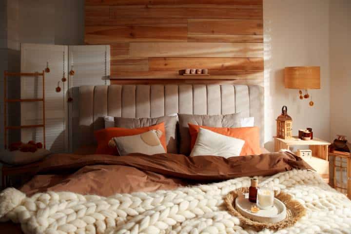 Cozy bedroom interior with knitted blanket and cushions