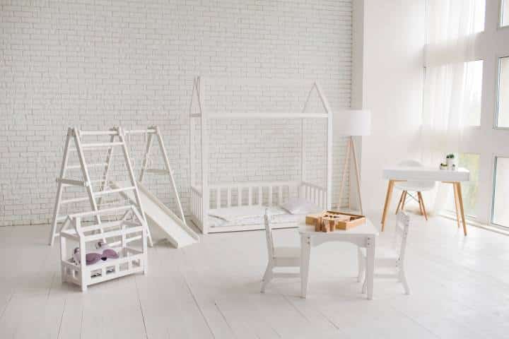 Kids room interior with white wooden bed, table with chairs and a sports complex