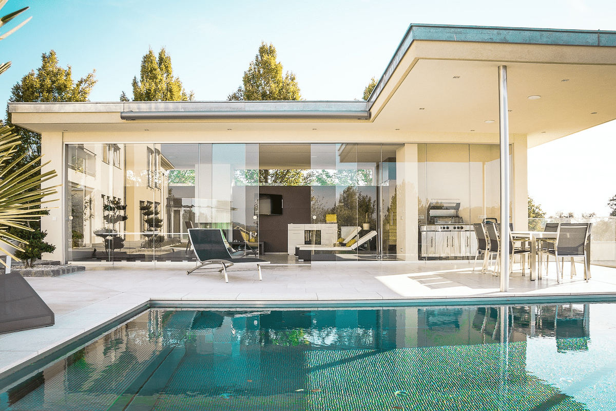 modern home with glass walls and metallic details in front of pool