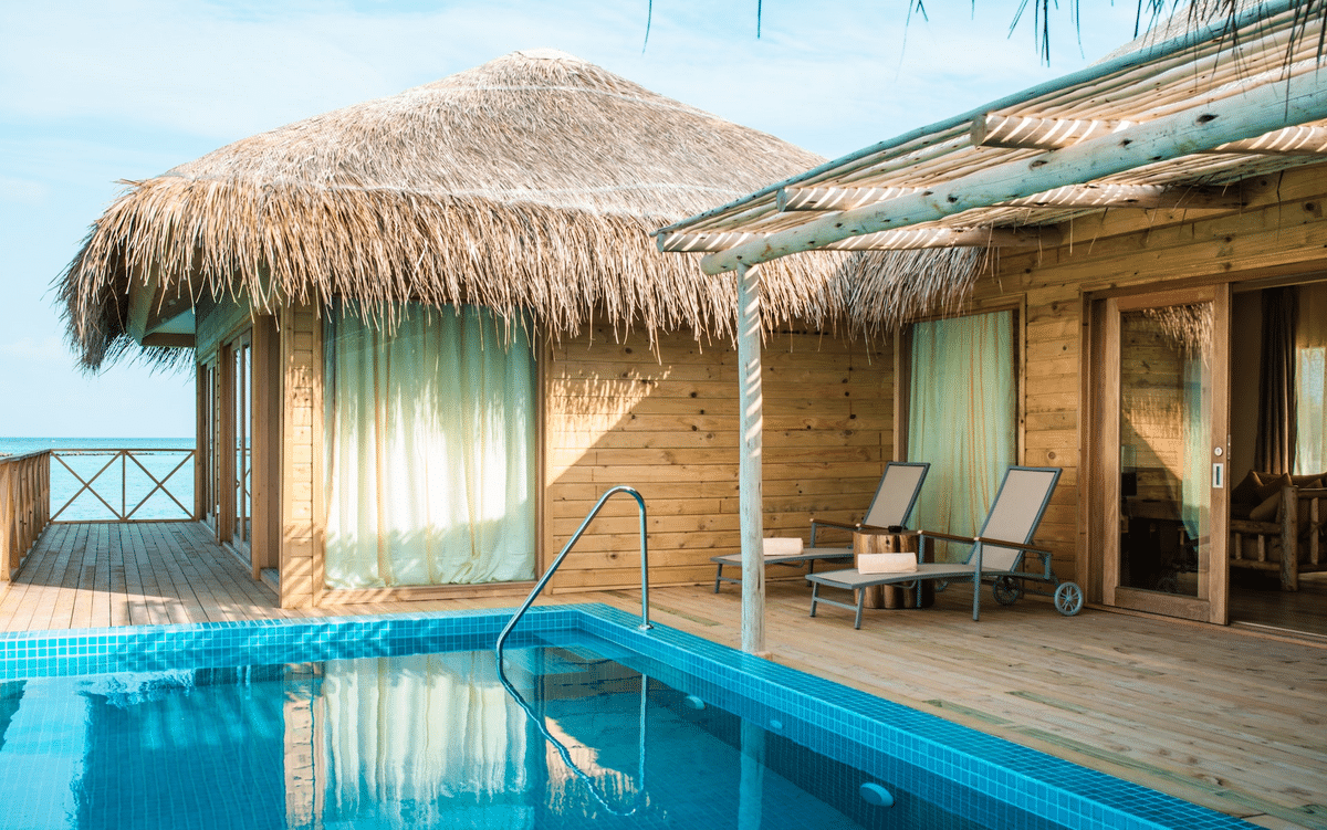 pool house in the style of a boho hut with sliding doors and pool chairs