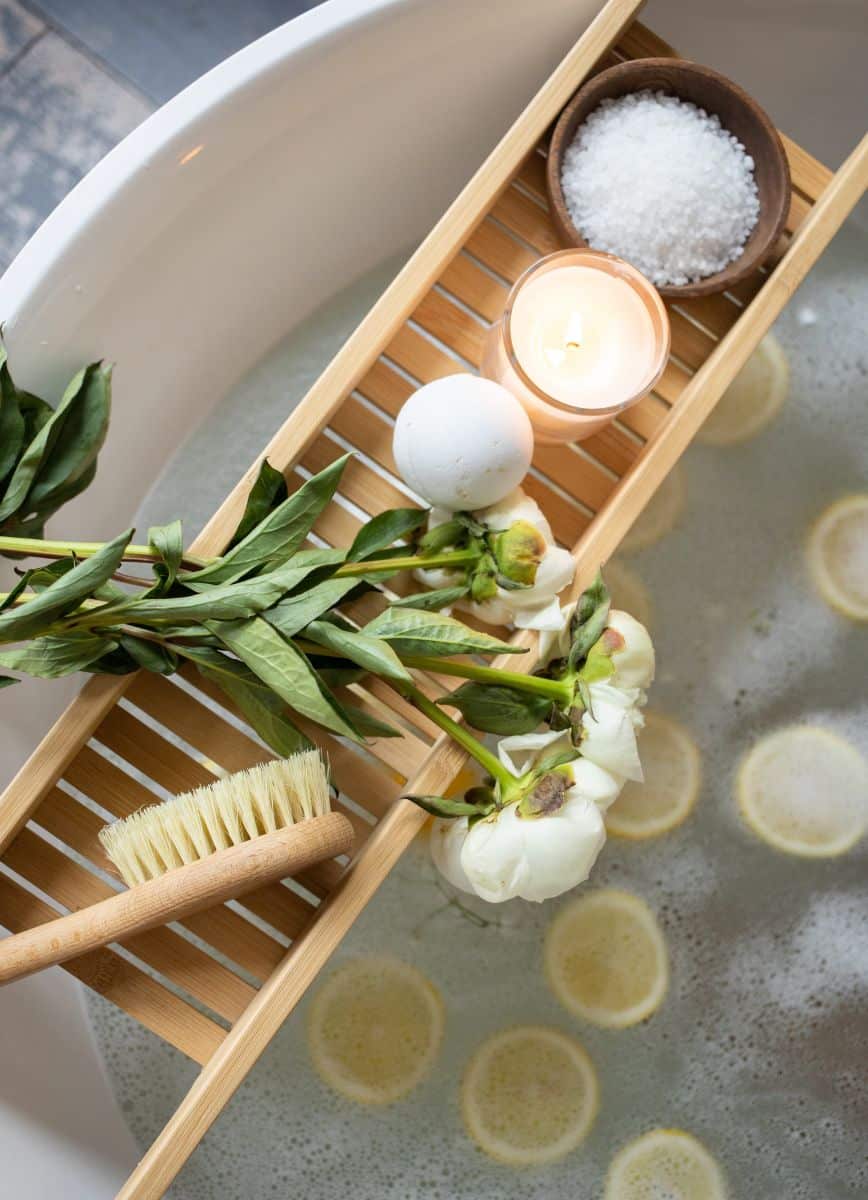 DIY spa with bath bomb, bath salt, and white roses on bathtub tray 