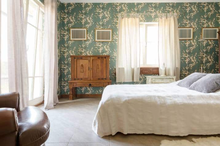 Grand bedroom in classic style, with antique chest of drawers and elegant floral wallpaper