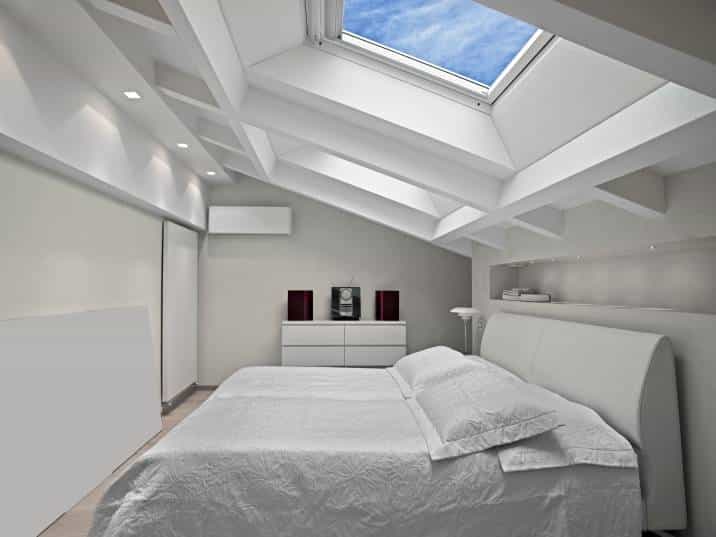 modern white bedroom with skylight showing blue sky