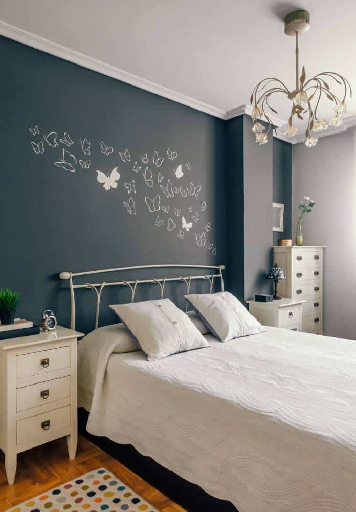 Bedroom with blackboard wall, butterflies mural. White bed and bedside tables 