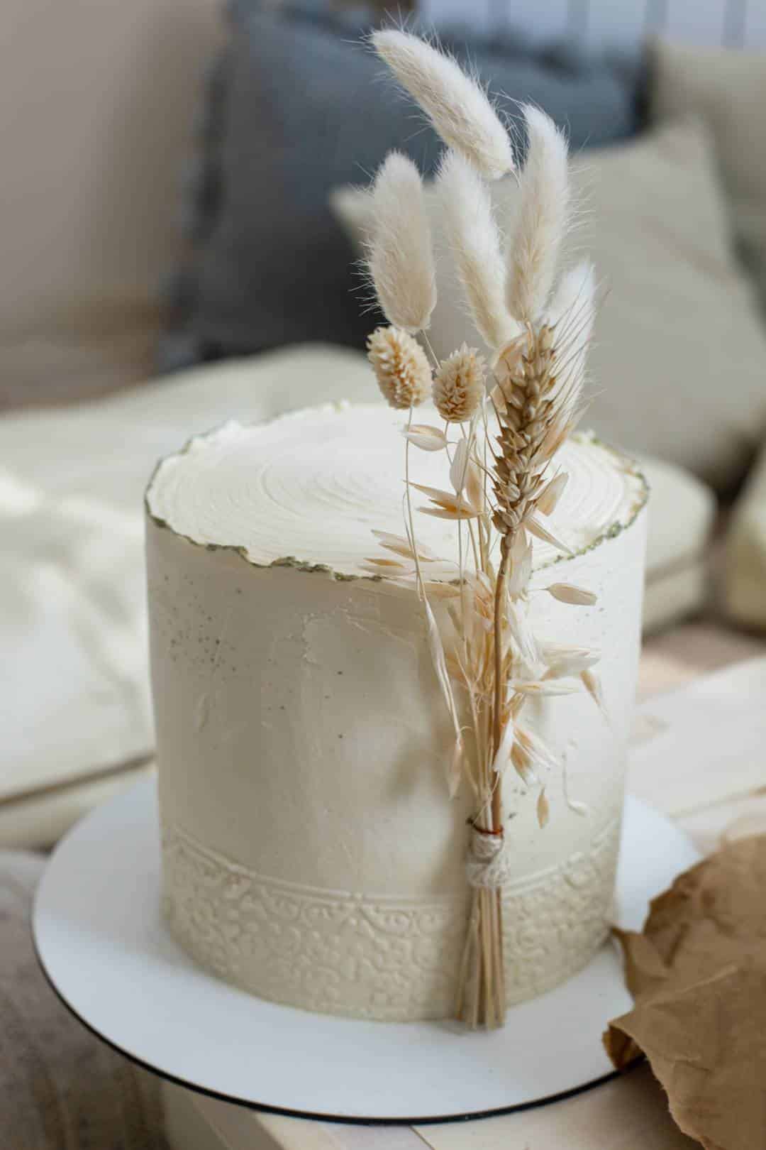 Wedding cake decorated with dry ear of wheat cotton in boho style