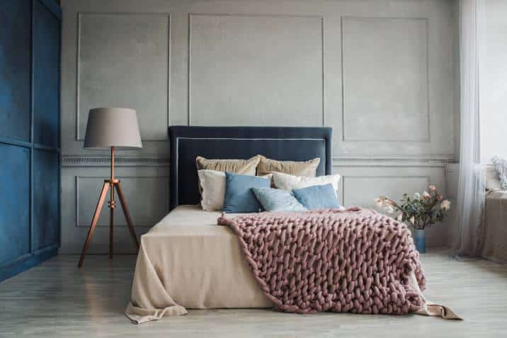 cosy modern bedroom with chunky knit throw blanket and craft floor lamp