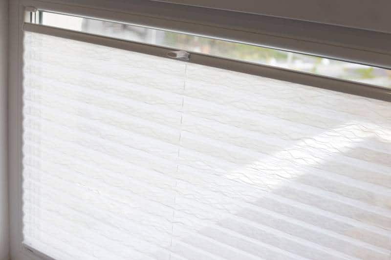 pleated cordless blinds close up on apartment window, white colour fabric