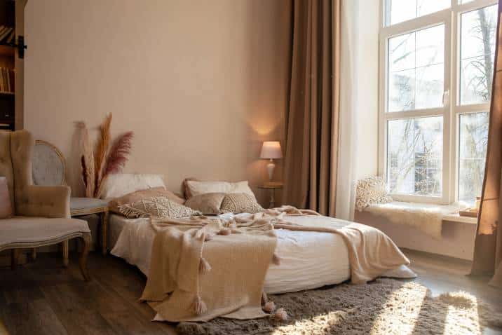 Interior of a large bedroom. Lots of light from a large window, a comfortable, soft bed