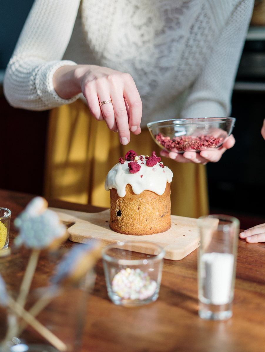 Holding glass jar with dry berries, decorating cake for Mother’s Day gift