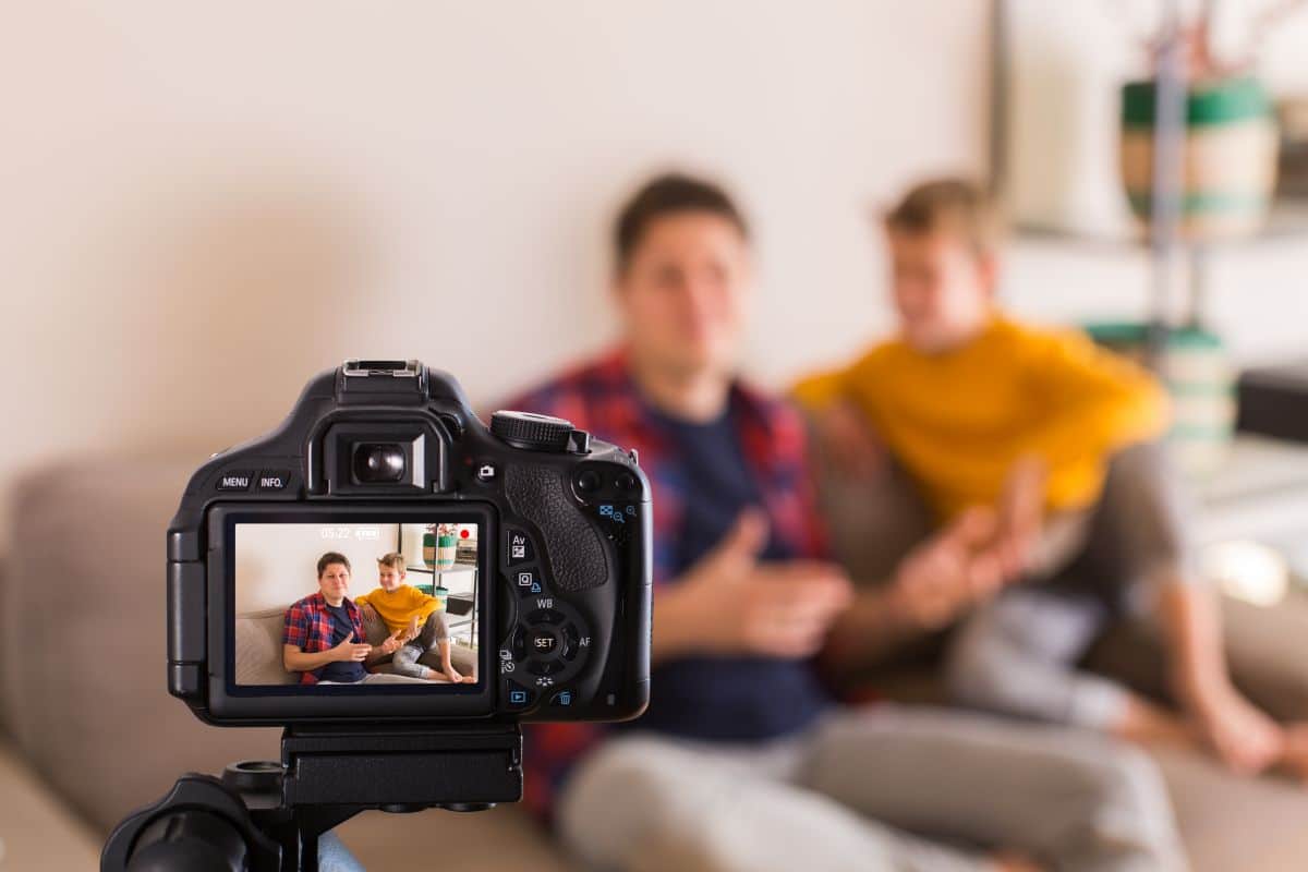 Father and son recording a Mother's Day video while sitting on couch