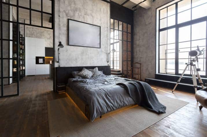 Luxury studio apartment bedroom in a loft style in dark colours. Glass grid and concrete wall