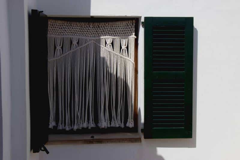window with typical Majorcan shutters and a macramé curtain