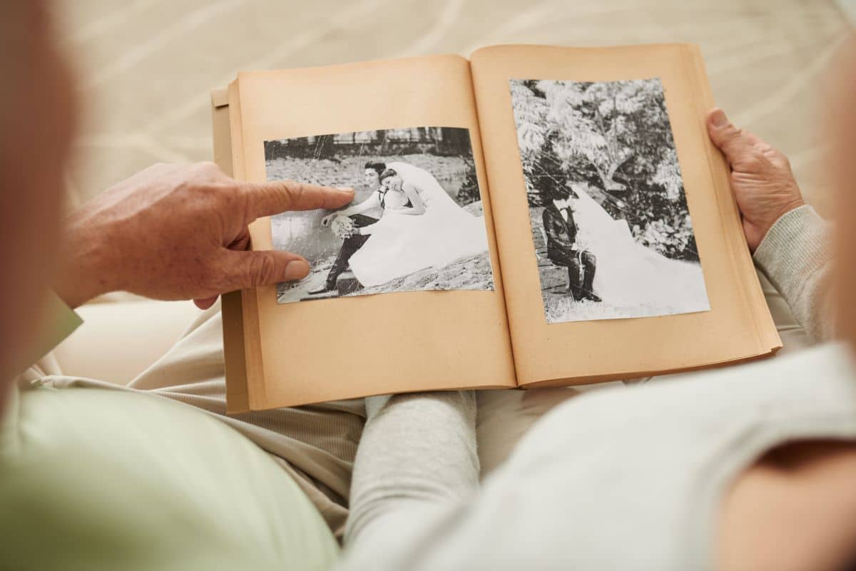 Senior couple looking at their restored wedding photos in photo album, sentimental Mother's Day gift