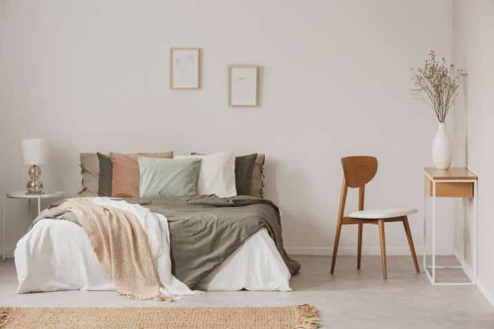 stylish chair next to warm king size bed in Scandinavian bedroom