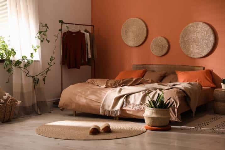 Bed with orange and brown linens in stylish room interior