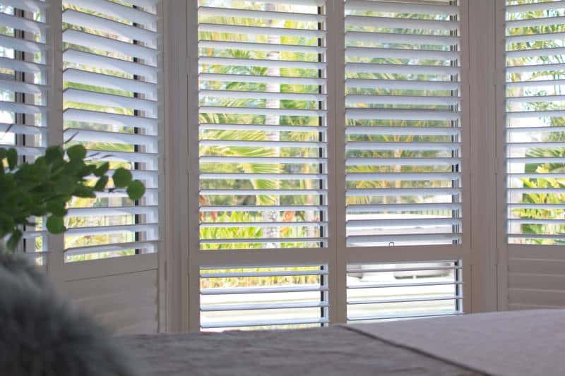 luxury white indoor plantation shutters in bedroom 