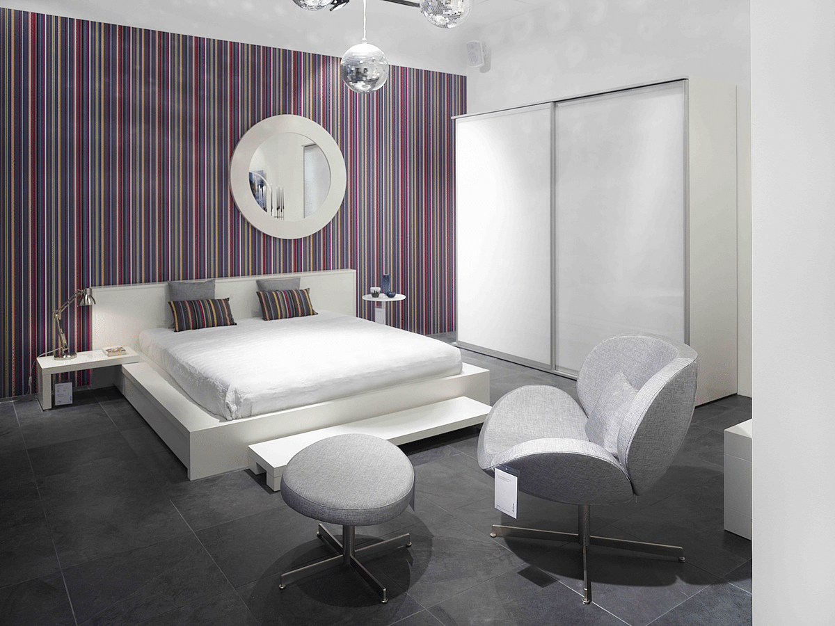 bedroom with a colourful accent wall and matching pillows, with a disco ball as a chandelier above the bed