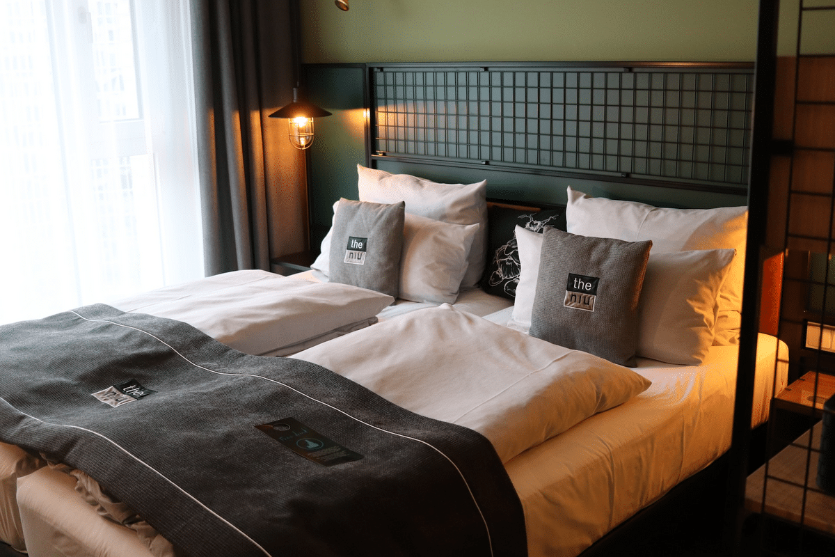 White throw pillows on a white bed with metal bed frame next to industrial cage light