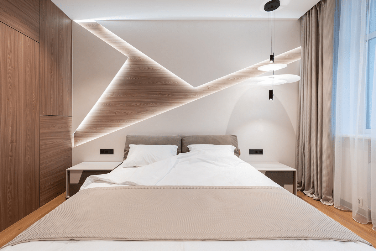 Modern bedroom with wooden walls and a large bed at the centre with lights integrated in wall feature