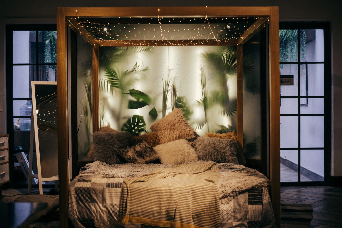grey bed with fuzzy pillows, wooden bedframe with string lights hung on it